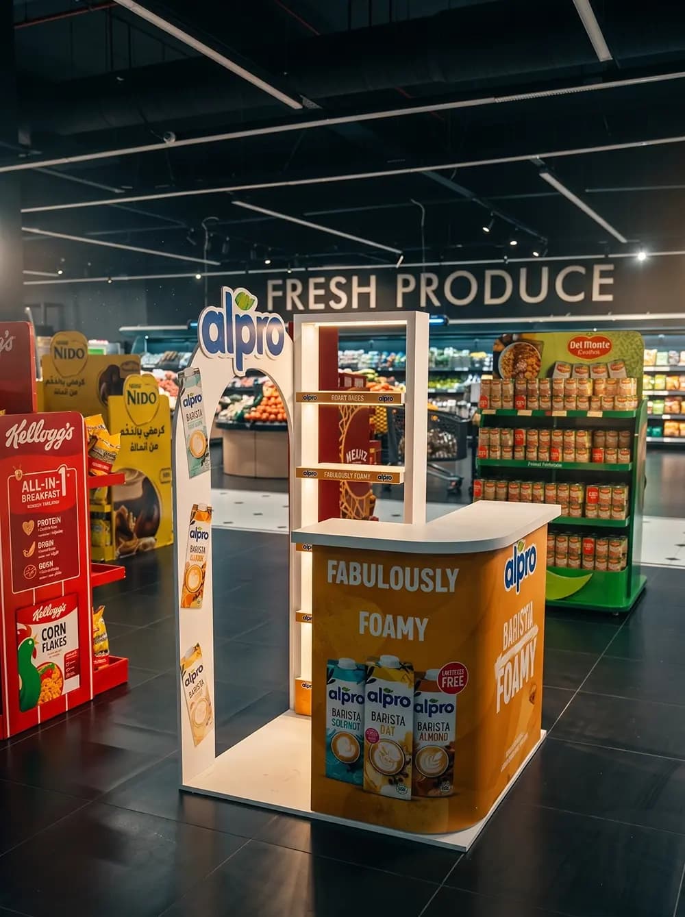 Alpro in-store sampling stand with an arched frame and branded counter built by Proink