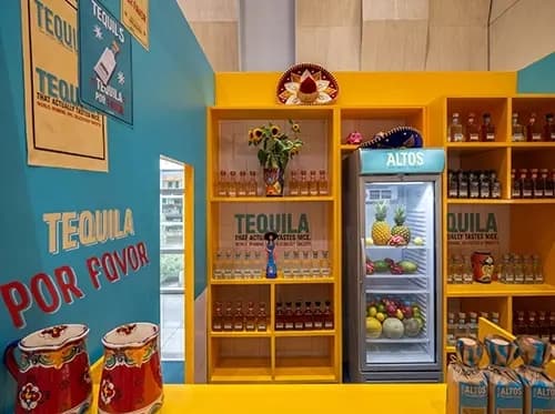 Altos tequila display shelving with a branded cooler, ceramics and sunflowers