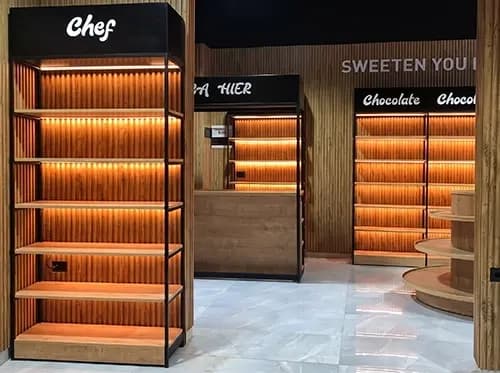 Confectionery store interior with continuous backlit shelving and category signage