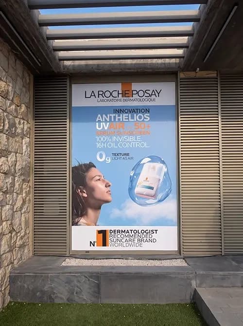 Illuminated La Roche-Posay Anthelios poster mounted in a stone wall recess