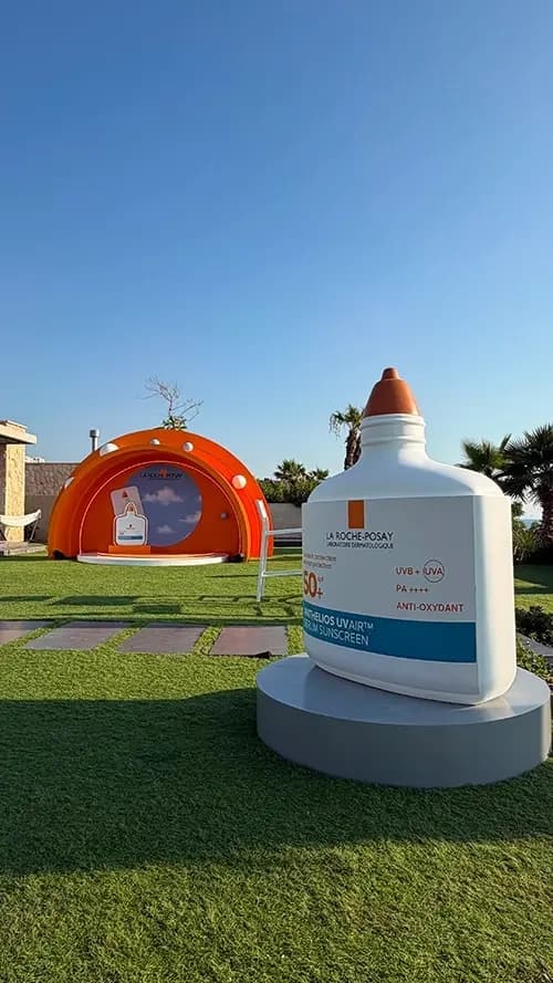 Oversized Anthelios sunscreen replica standing beside the orange arch structure