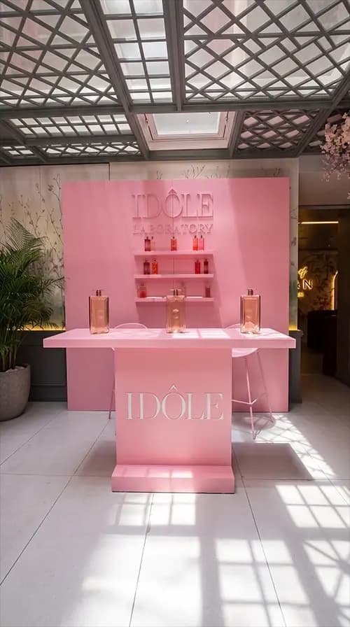 Idôle Laboratory counter presenting fragrance on a pink podium with tiered shelving