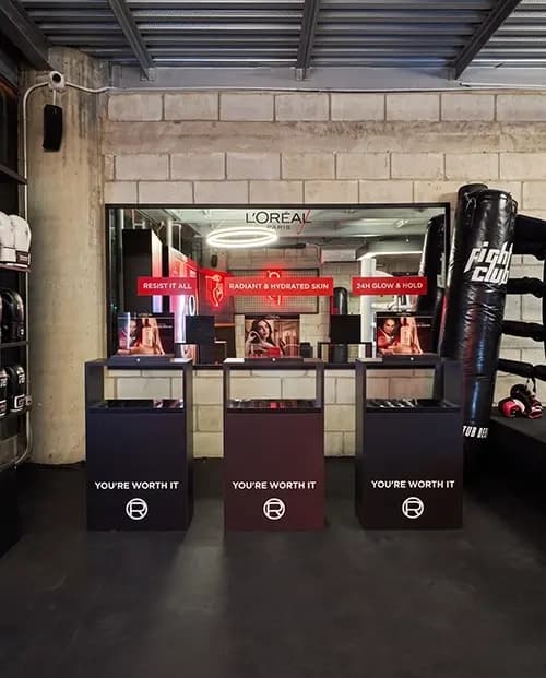 Mirrored L'Oréal consultation stations installed beside boxing equipment