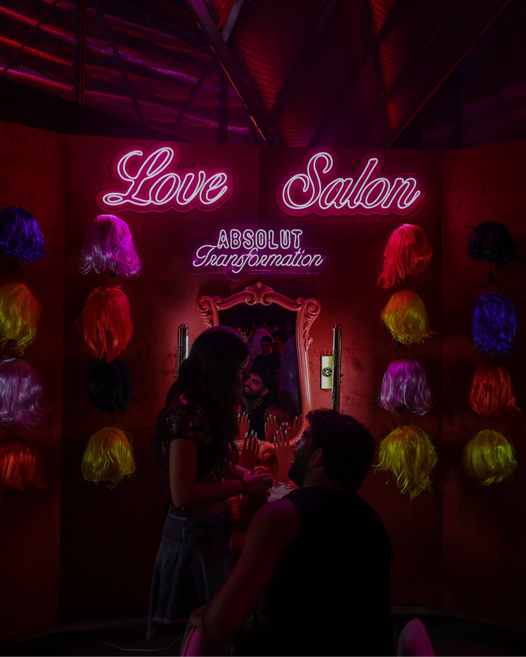 Love Salon neon sign above a wall of wigs at the Absolut Love Night transformation station