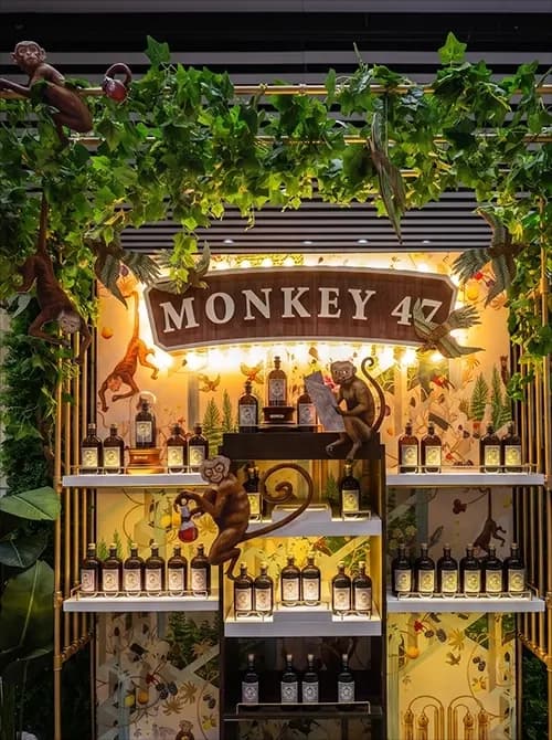 Monkey 47 activation stand installed in a retail venue with printed mural panels and greenery