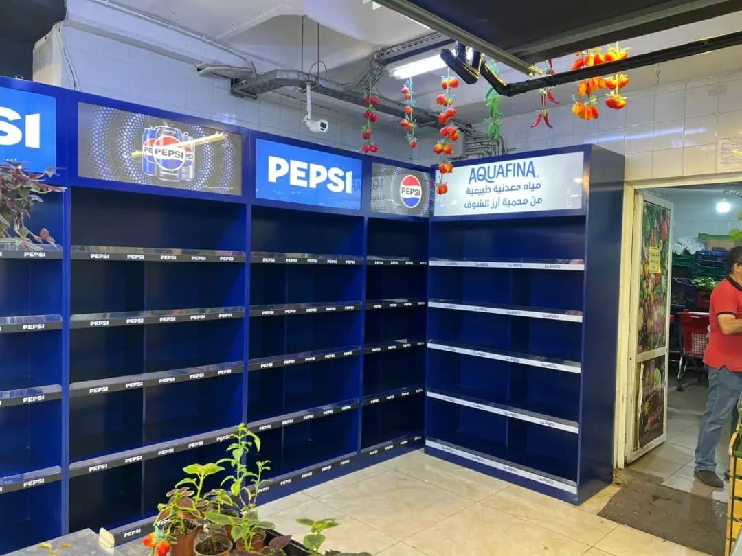 Blue Pepsi and Aquafina shelving with illuminated header panels in a neighbourhood market